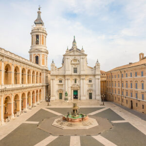 Square of Loreto, Basilica della Santa Casa in sunny day, portico to the side, people in the square in Loreto, Ancona, Italy